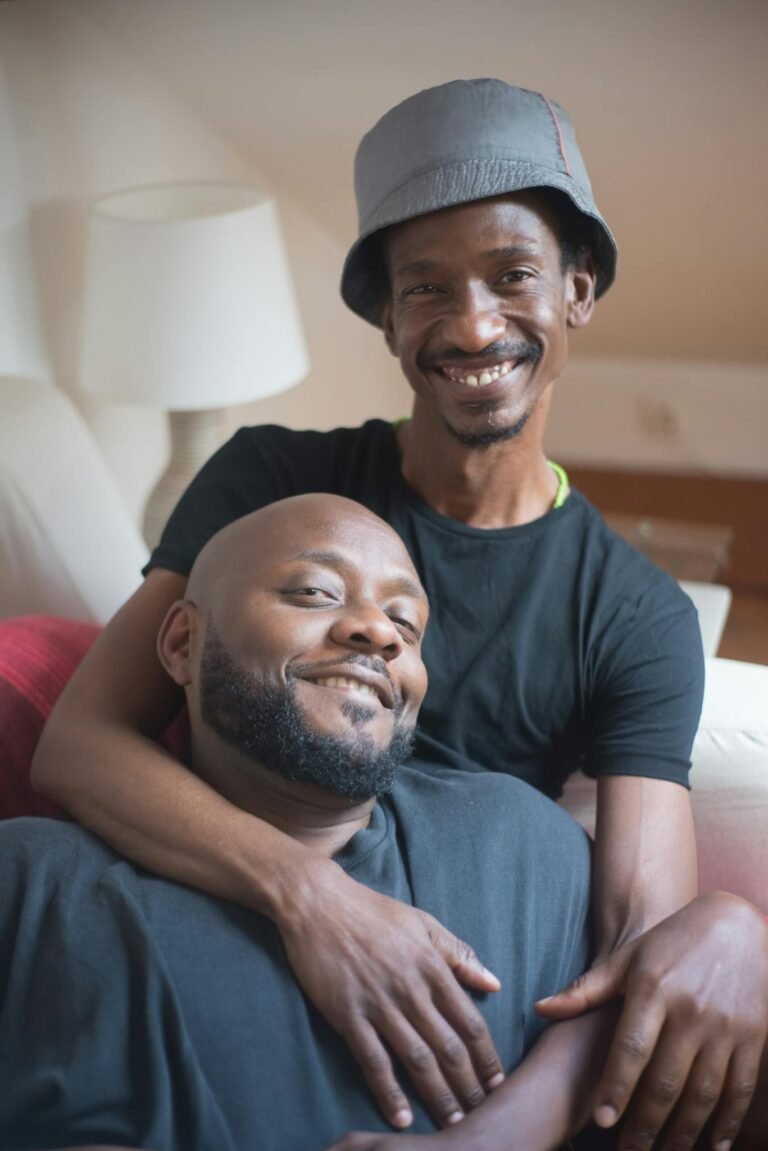 A joyful couple relaxing together on the couch indoors, embracing and smiling.
