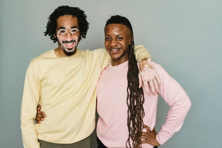 Two men with vitiligo embracing in a studio shot, symbolizing unity and diversity.